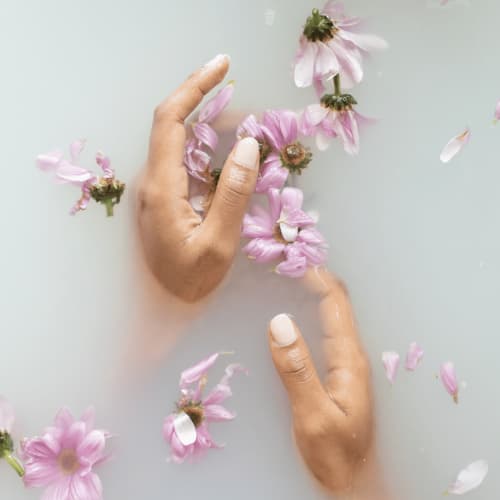 Hænder i spa vand med blomster del af neglebehandling hos BeautyByDau i Sønderborg.