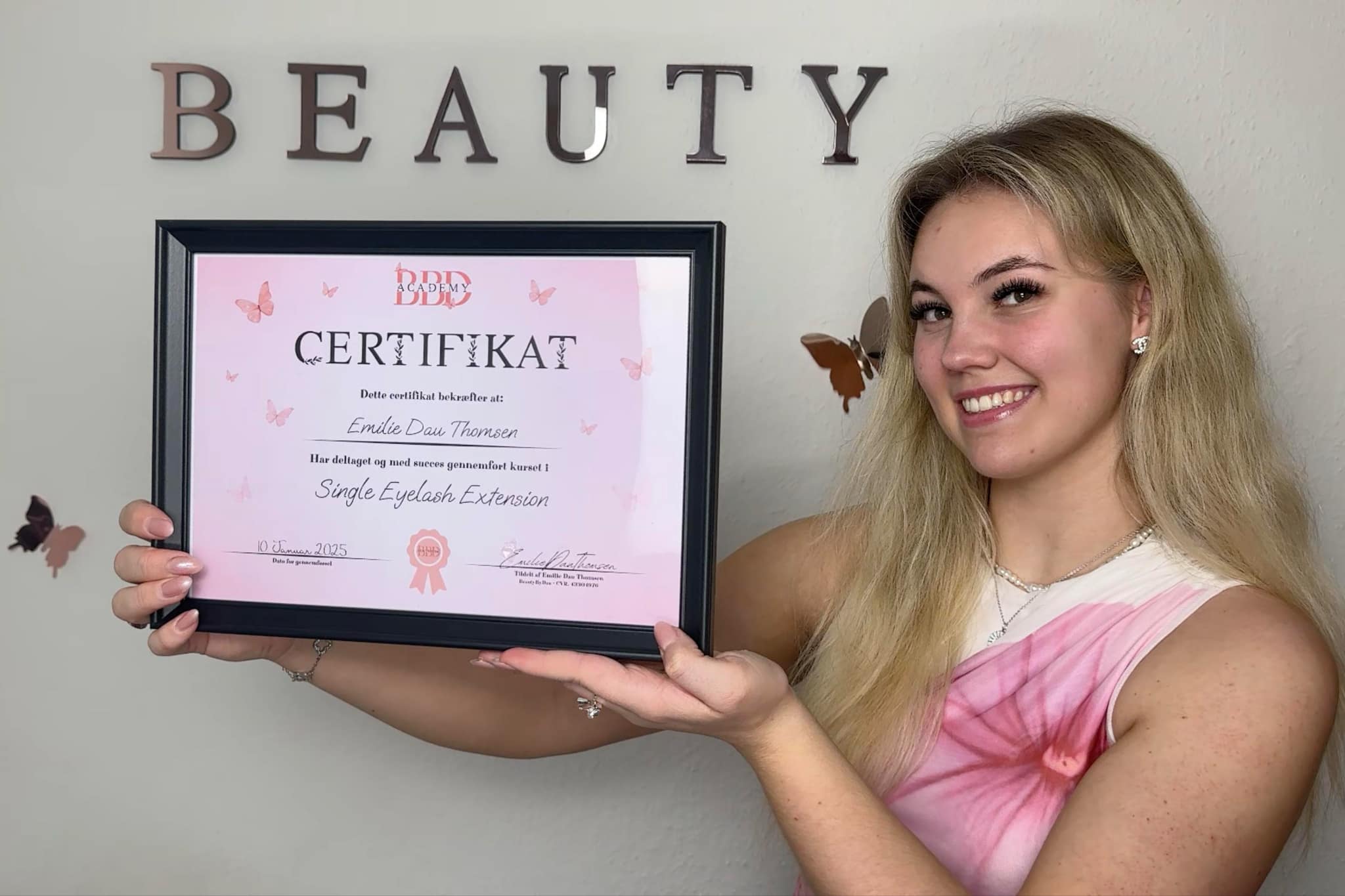 Emilie Dau Thomsen viser sit officielle vippetekniker-certifikat, som udstedes til kursister der gennemfører Vippetekniker Kursus hos BeautyByDau i Sønderborg.